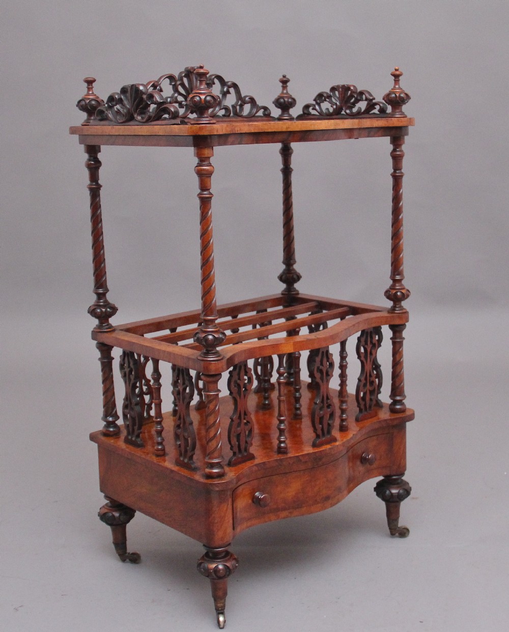 A 19th-century Victorian burr walnut music Canterbury featuring spiral twist support columns, pierced fretwork partitions, a serpentine lower drawer with turned wooden handles, and small brass castors. View II