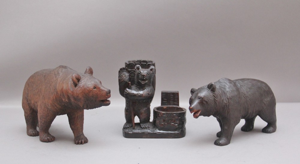 A set of three nineteenth-century hand-carved dark wood Black Forest bear figures, including two standing bears and one central desk accessory bear.