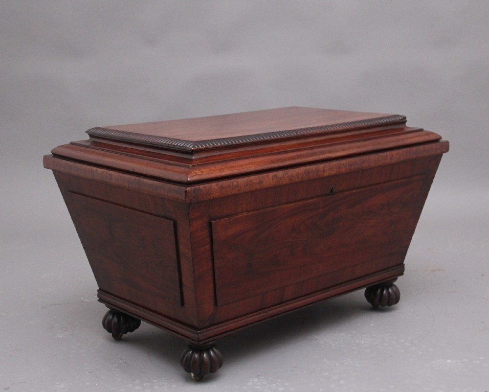 A 19th-century mahogany cellarette of sarcophagus form featuring a stepped lid, panelled sides, and carved gadrooned feet with castors.