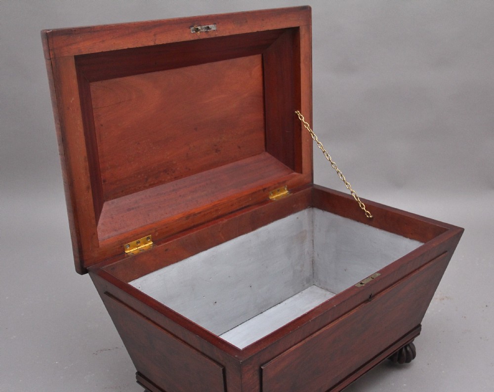 A 19th-century mahogany cellarette of sarcophagus form featuring a stepped lid, panelled sides, and carved gadrooned feet with castors. View III