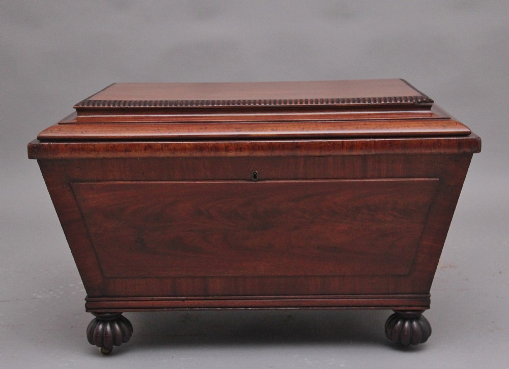 A 19th-century mahogany cellarette of sarcophagus form featuring a stepped lid, panelled sides, and carved gadrooned feet with castors. View VI