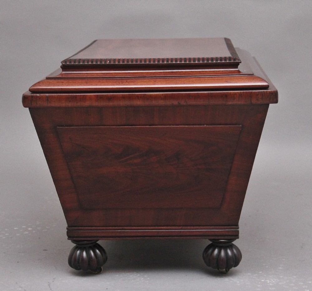 A 19th-century mahogany cellarette of sarcophagus form featuring a stepped lid, panelled sides, and carved gadrooned feet with castors. View IX
