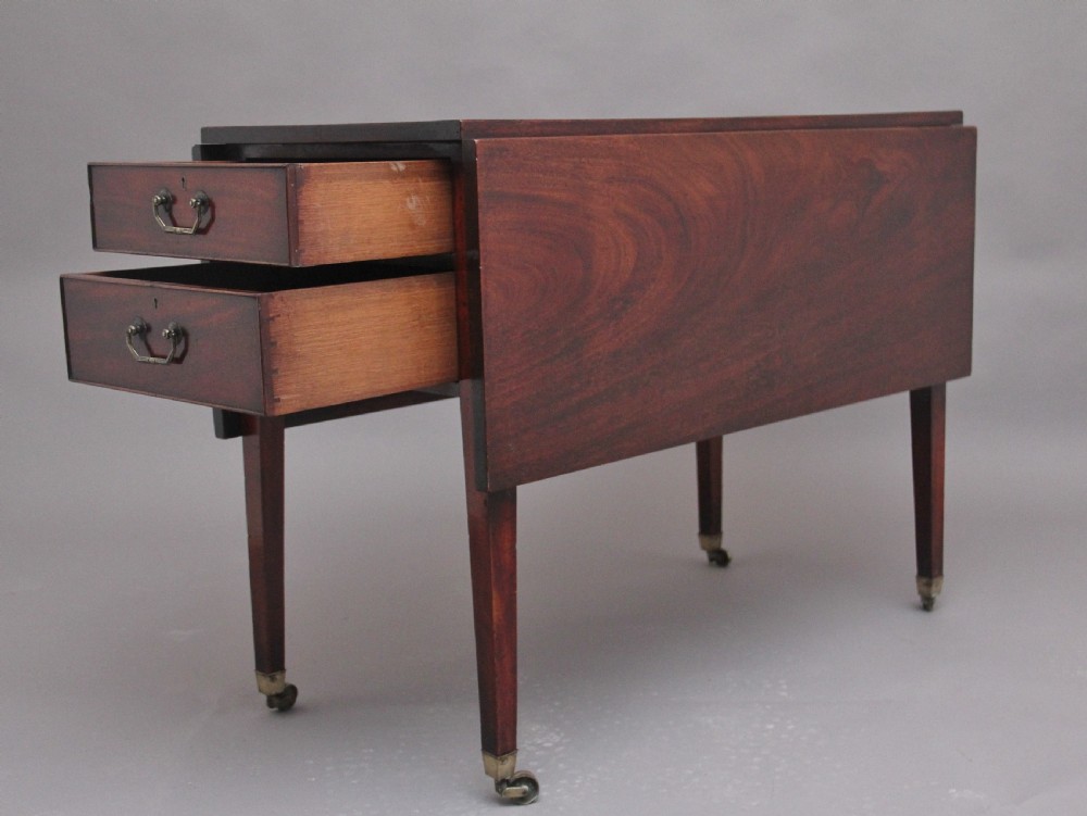 An 18th-century mahogany drop-leaf side table featuring two end drawers with brass bail handles and square tapered legs ending in brass castors. View X