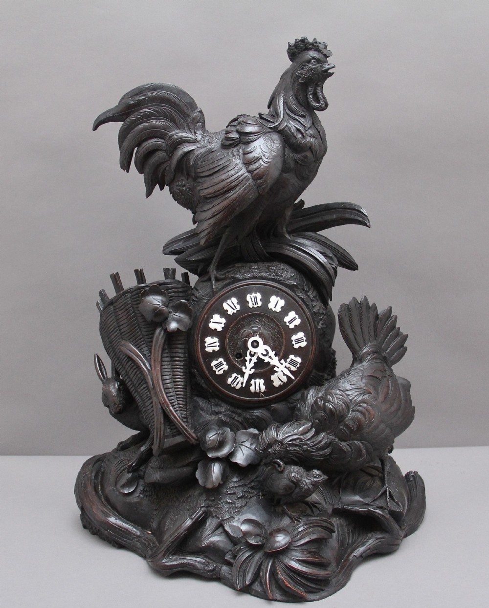 A 19th-century carved dark wood Black Forest mantel clock featuring a cockerel finial, foliage motifs, and a central circular clock face with Roman numerals.