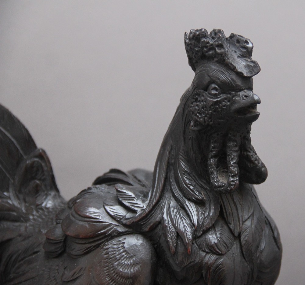 A 19th-century carved dark wood Black Forest mantel clock featuring a cockerel finial, foliage motifs, and a central circular clock face with Roman numerals. View VIII