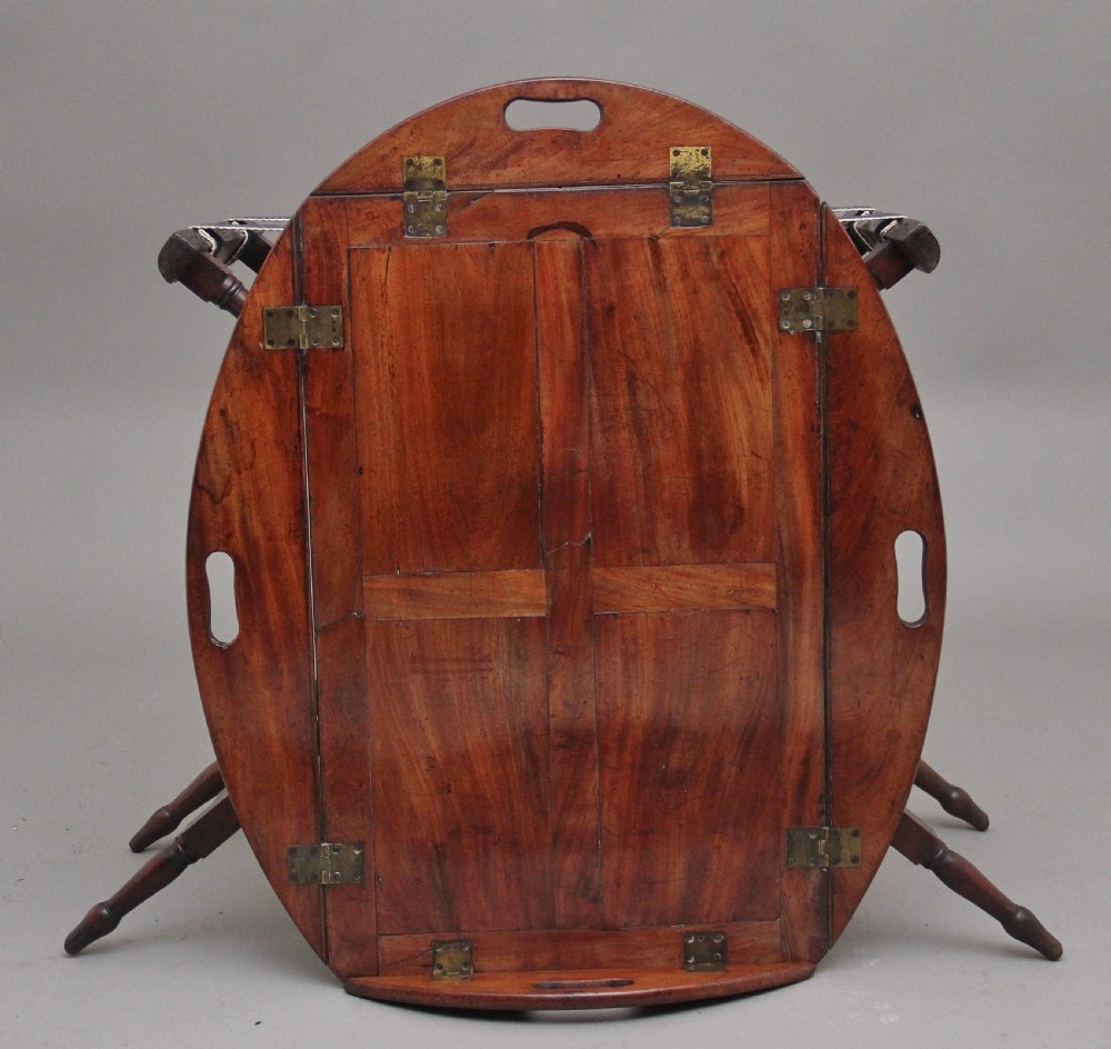 An early nineteenth-century dark mahogany butler tray with curved gallery sides and cut-out handles resting on a folding X-frame stand. View III