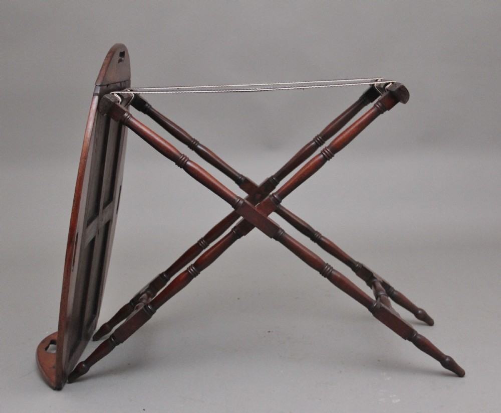 An early nineteenth-century dark mahogany butler tray with curved gallery sides and cut-out handles resting on a folding X-frame stand. View VIII
