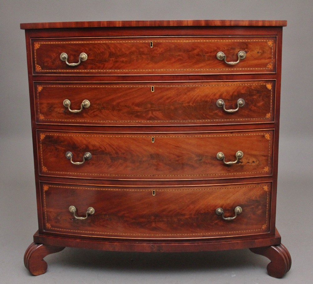 An early nineteenth-century flame mahogany bowfront chest featuring four graduated drawers with inlaid banding and brass handles.