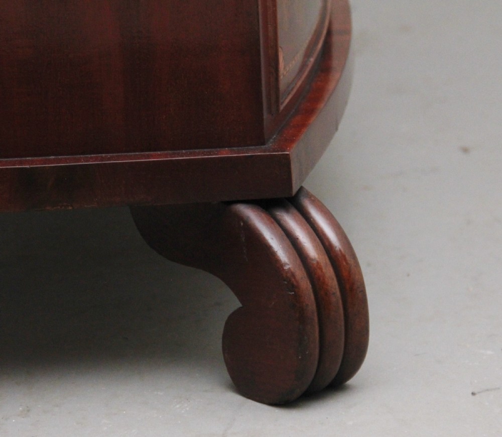 An early nineteenth-century flame mahogany bowfront chest featuring four graduated drawers with inlaid banding and brass handles. View XII