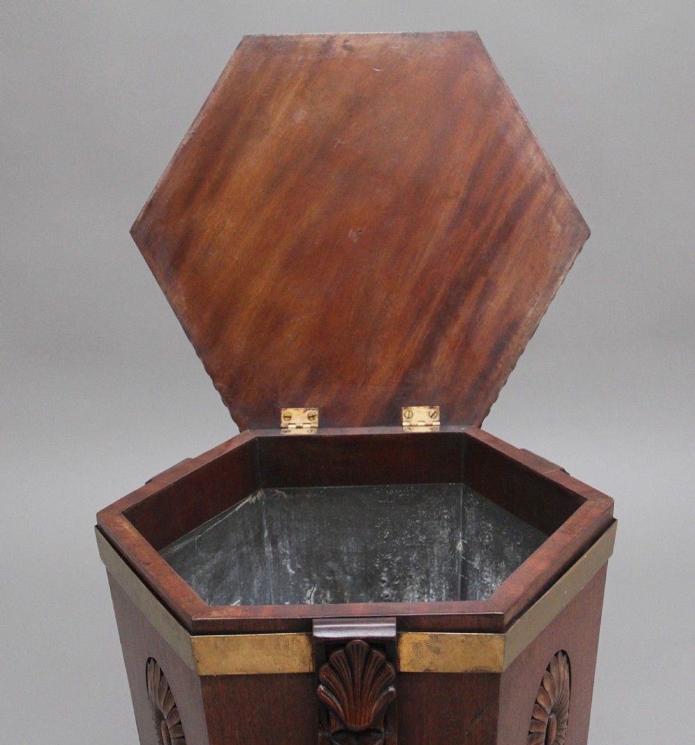 An early twentieth-century mahogany wine cooler featuring a gadrooned hinged lid with turned finial, brass strapping, carved rosette details, and carved dolphin legs. View III