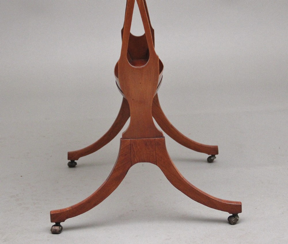 A 19th-century Sheraton Revival satinwood serving table featuring a tray top, pierced side supports, a lower shelf, and splayed legs on brass castors. View XII