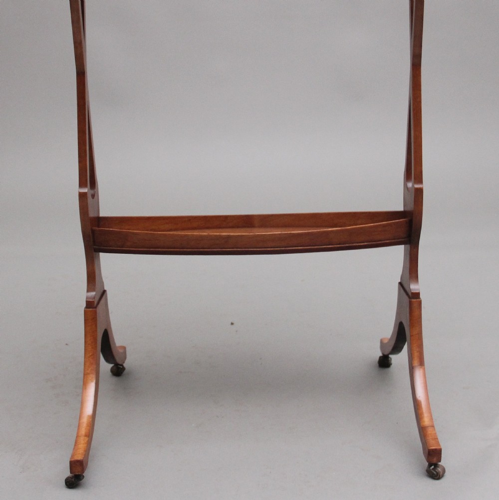 A 19th-century Sheraton Revival satinwood serving table featuring a tray top, pierced side supports, a lower shelf, and splayed legs on brass castors. View XIII