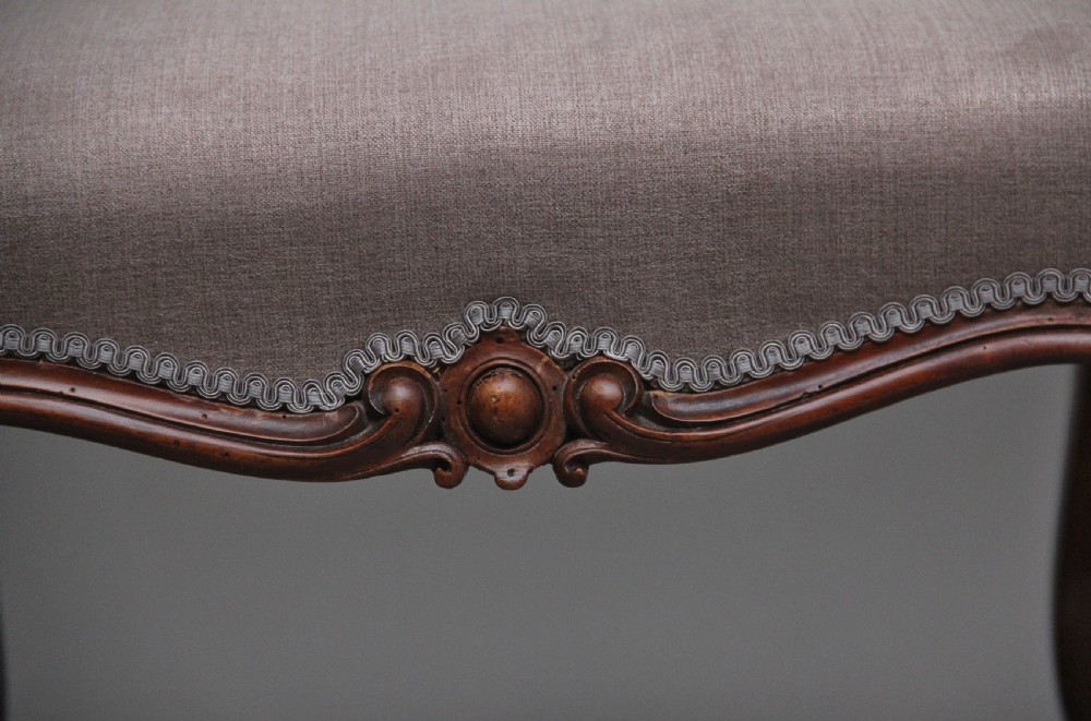 A nineteenth-century Victorian walnut footstool featuring carved cabriole legs, shaped aprons, and light grey fabric upholstery detailed with braided gimp trim. View VIII