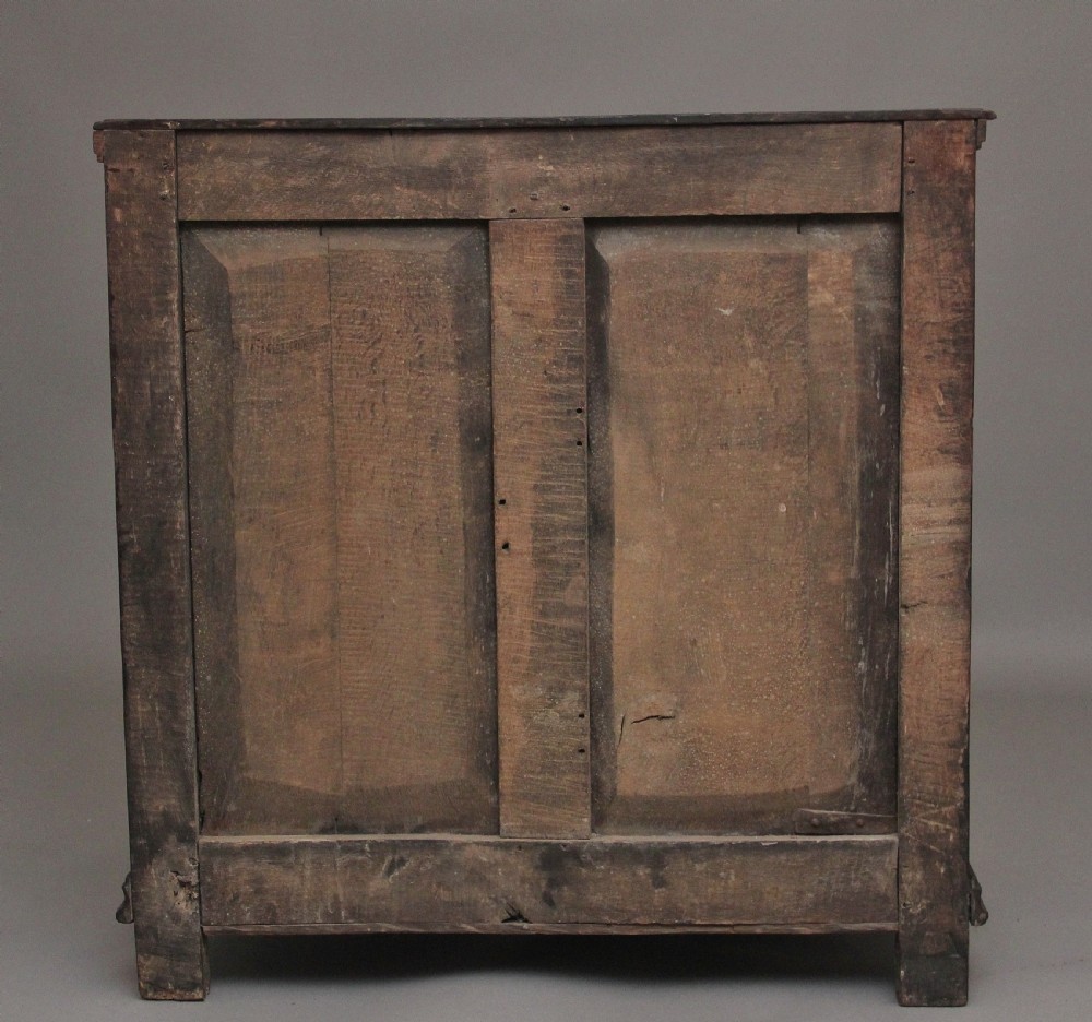 An early eighteenth century dark oak chest of drawers featuring geometric moulded drawer fronts, carved frieze, and brass drop handles. View VIII