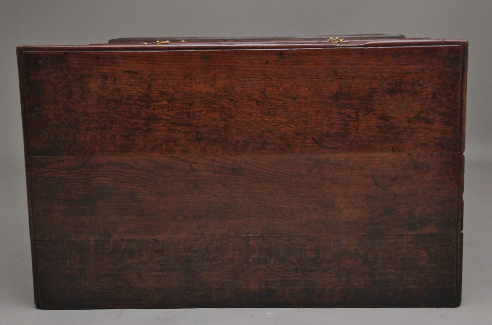 An early eighteenth century dark oak chest of drawers featuring geometric moulded drawer fronts, carved frieze, and brass drop handles. View X