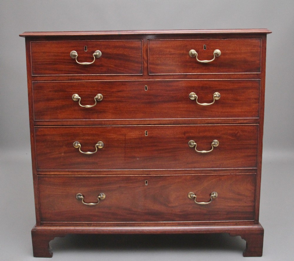 An early 19th-century flat-fronted mahogany chest of drawers featuring two short over three long drawers with brass handles and bracket feet.