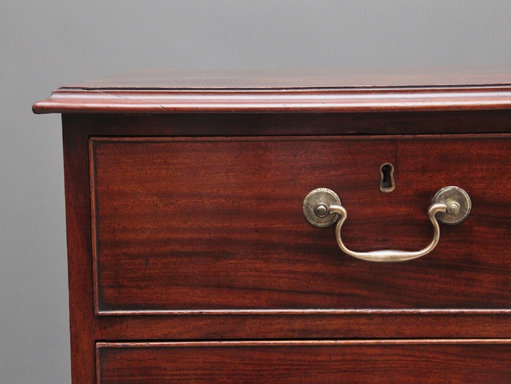 An early 19th-century flat-fronted mahogany chest of drawers featuring two short over three long drawers with brass handles and bracket feet. View II