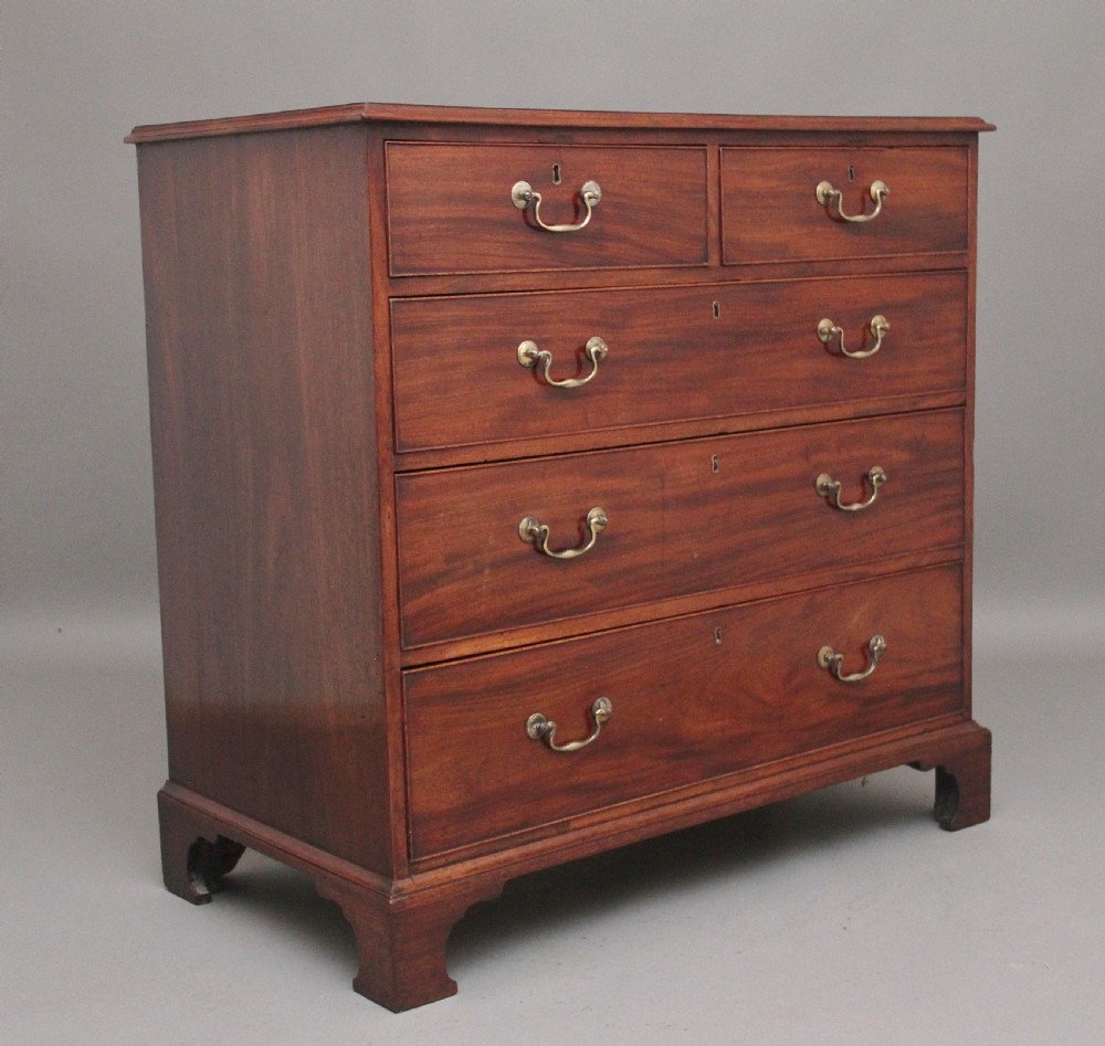 An early 19th-century flat-fronted mahogany chest of drawers featuring two short over three long drawers with brass handles and bracket feet. View III