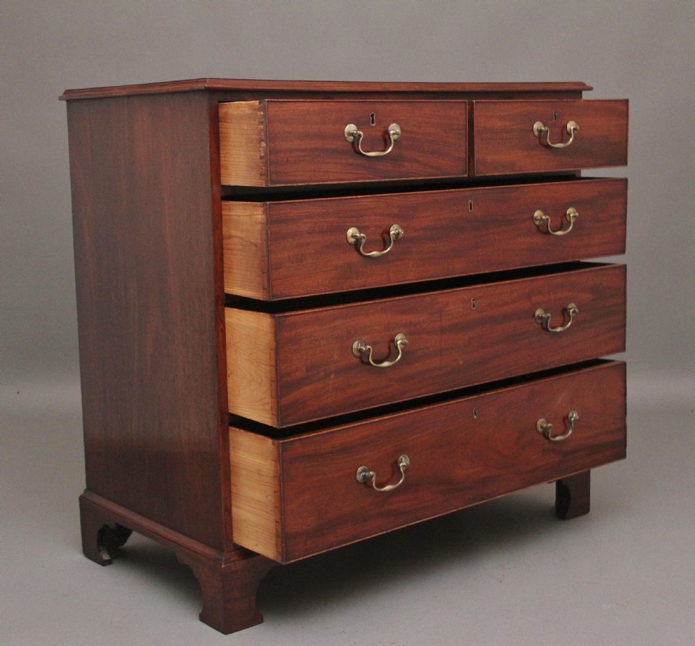 An early 19th-century flat-fronted mahogany chest of drawers featuring two short over three long drawers with brass handles and bracket feet. View V