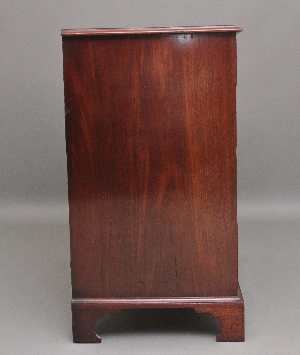 An early 19th-century flat-fronted mahogany chest of drawers featuring two short over three long drawers with brass handles and bracket feet. View VI