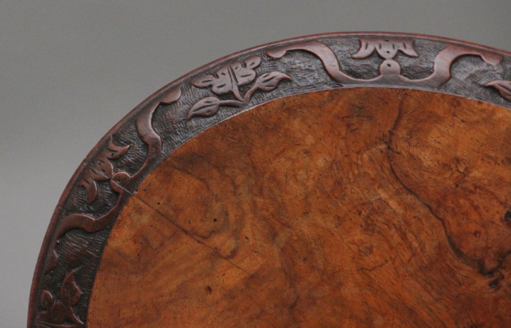 A 19th-century circular walnut occasional table featuring a carved rim, turned central column, and three carved cabriole tripod legs. View IV