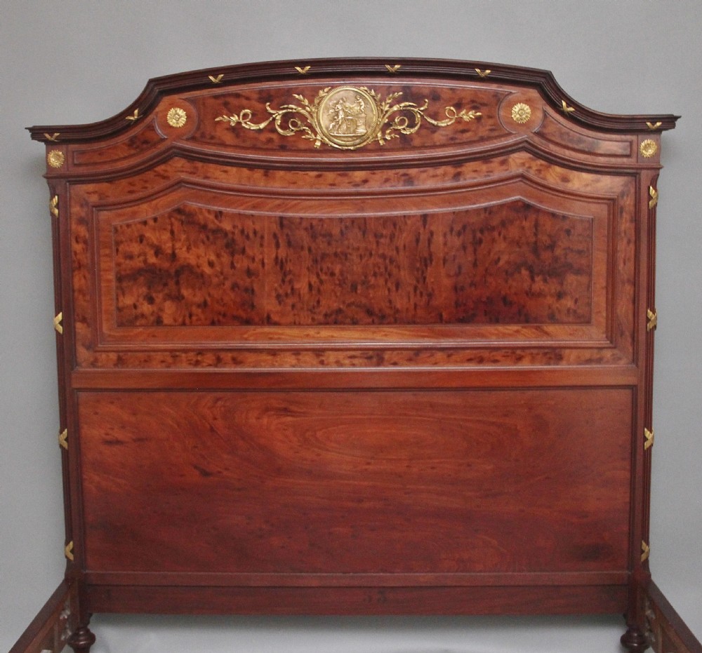A 19th-century French Neoclassical bed frame crafted from dark mottled mahogany featuring decorative brass scroll mounts and a carved central medallion. View II