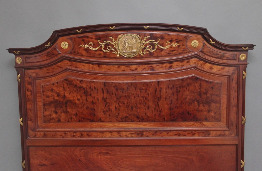A 19th-century French Neoclassical bed frame crafted from dark mottled mahogany featuring decorative brass scroll mounts and a carved central medallion. View III