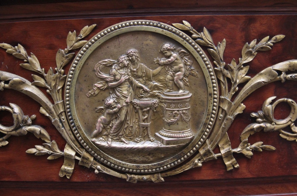 A 19th-century French Neoclassical bed frame crafted from dark mottled mahogany featuring decorative brass scroll mounts and a carved central medallion. View VI