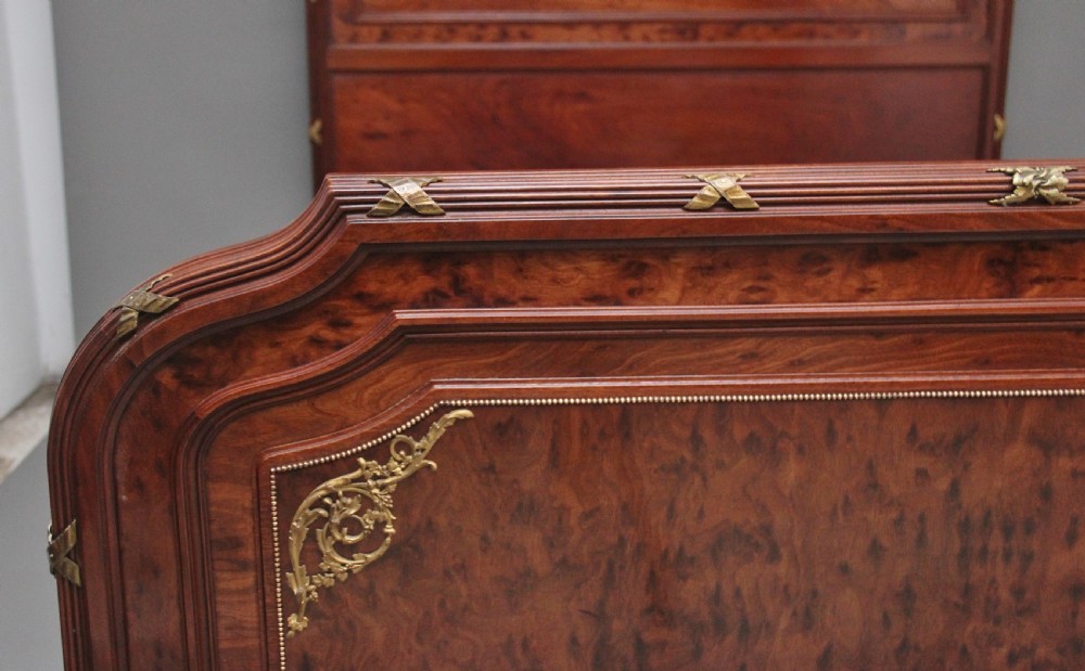 A 19th-century French Neoclassical bed frame crafted from dark mottled mahogany featuring decorative brass scroll mounts and a carved central medallion. View X