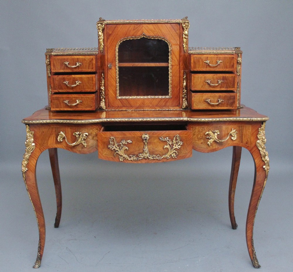 A 19th-century walnut writing desk featuring ornamental gilt-bronze mounts, cabriole legs, and a raised central glazed cabinet flanked by drawers. View II