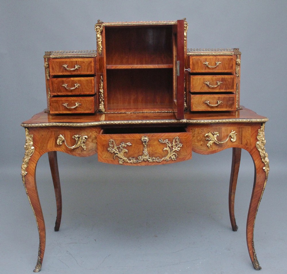 A 19th-century walnut writing desk featuring ornamental gilt-bronze mounts, cabriole legs, and a raised central glazed cabinet flanked by drawers. View III