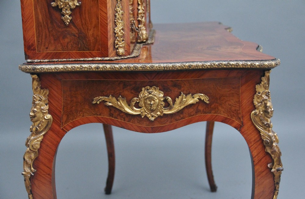 A 19th-century walnut writing desk featuring ornamental gilt-bronze mounts, cabriole legs, and a raised central glazed cabinet flanked by drawers. View IX