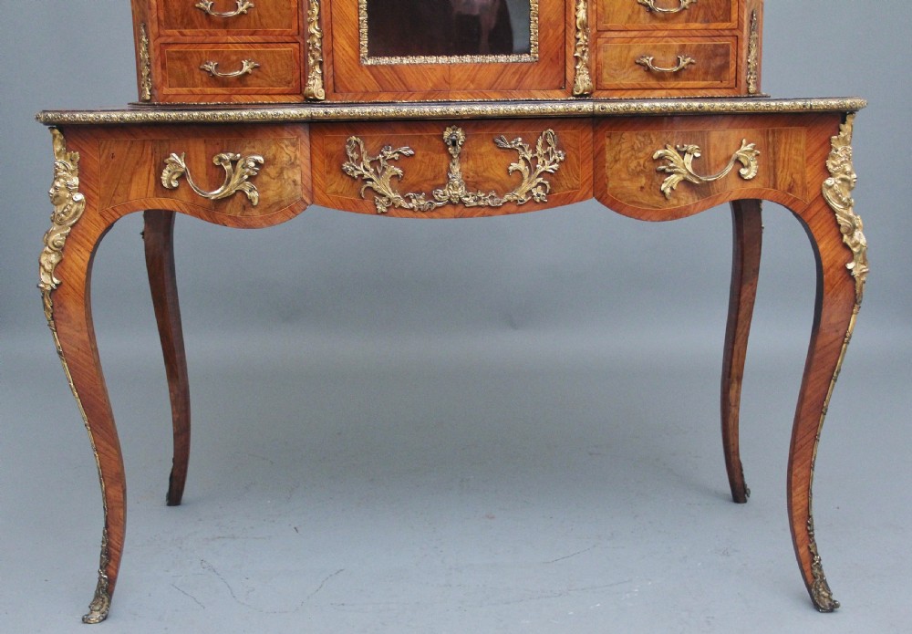 A 19th-century walnut writing desk featuring ornamental gilt-bronze mounts, cabriole legs, and a raised central glazed cabinet flanked by drawers. View XII