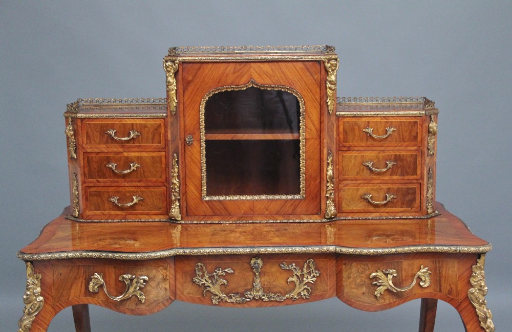 A 19th-century walnut writing desk featuring ornamental gilt-bronze mounts, cabriole legs, and a raised central glazed cabinet flanked by drawers. View XIII