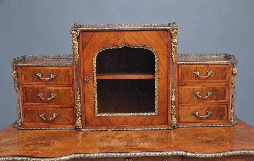 A 19th-century walnut writing desk featuring ornamental gilt-bronze mounts, cabriole legs, and a raised central glazed cabinet flanked by drawers. View XIV