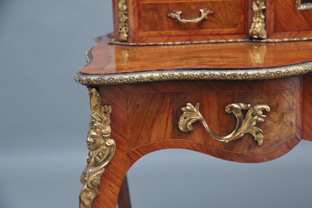 A 19th-century walnut writing desk featuring ornamental gilt-bronze mounts, cabriole legs, and a raised central glazed cabinet flanked by drawers. View XXI