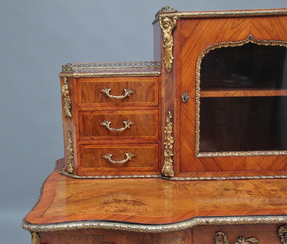 A 19th-century walnut writing desk featuring ornamental gilt-bronze mounts, cabriole legs, and a raised central glazed cabinet flanked by drawers. View XXIII