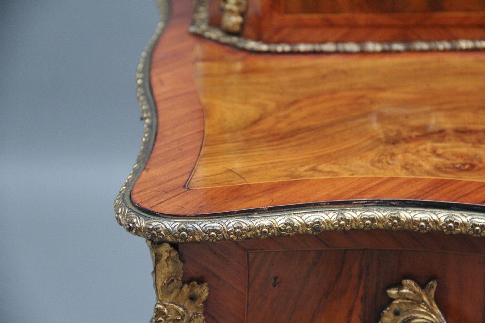 A 19th-century walnut writing desk featuring ornamental gilt-bronze mounts, cabriole legs, and a raised central glazed cabinet flanked by drawers. View XXV