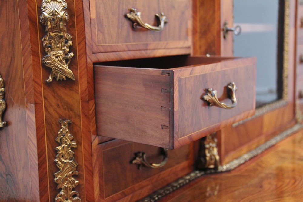 A 19th-century walnut writing desk featuring ornamental gilt-bronze mounts, cabriole legs, and a raised central glazed cabinet flanked by drawers. View XXVI