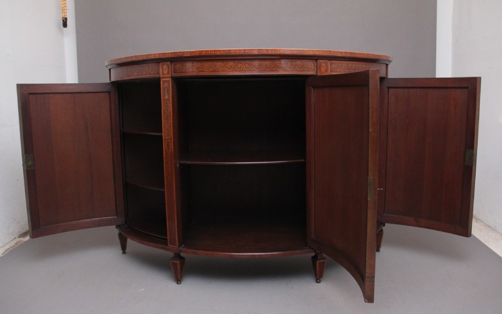 A 19th-century curved mahogany cabinet featuring intricate satinwood marquetry panels depicting classical figures, swags, and scrollwork. View II