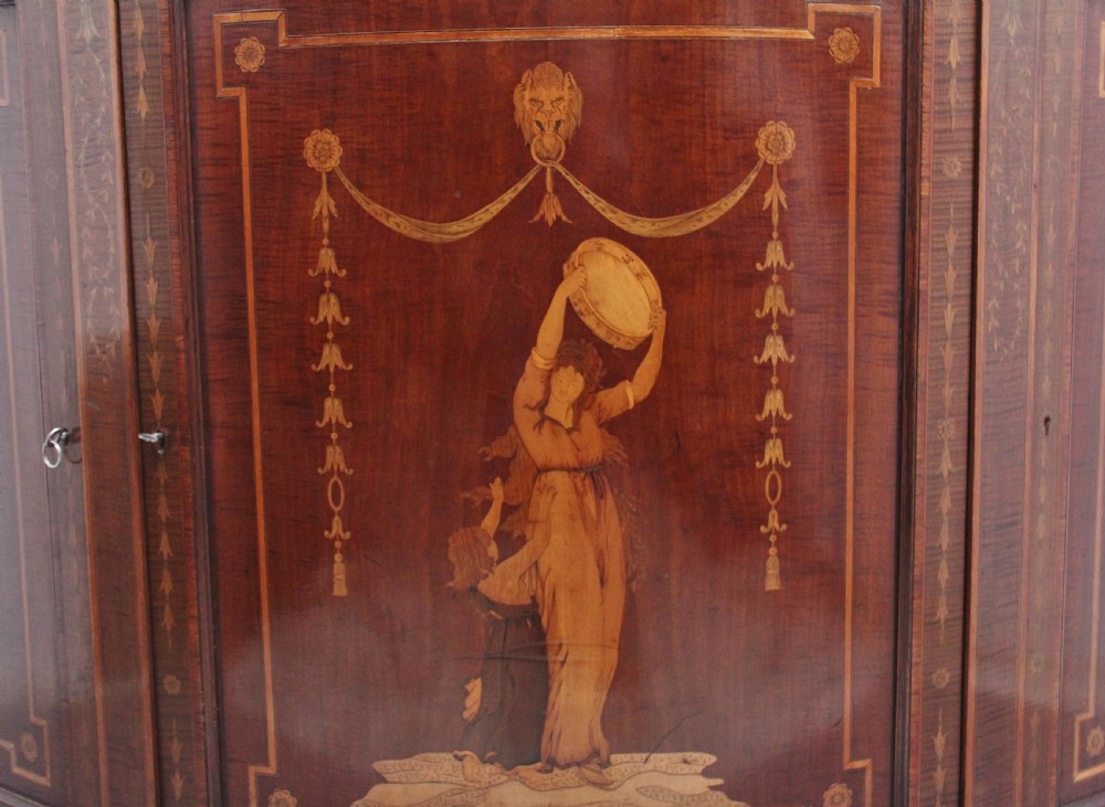 A 19th-century curved mahogany cabinet featuring intricate satinwood marquetry panels depicting classical figures, swags, and scrollwork. View XII