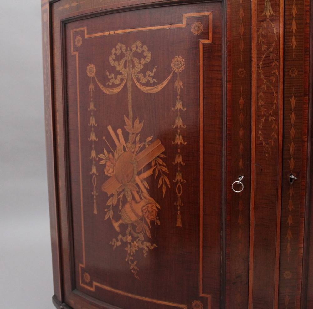 A 19th-century curved mahogany cabinet featuring intricate satinwood marquetry panels depicting classical figures, swags, and scrollwork. View XIII