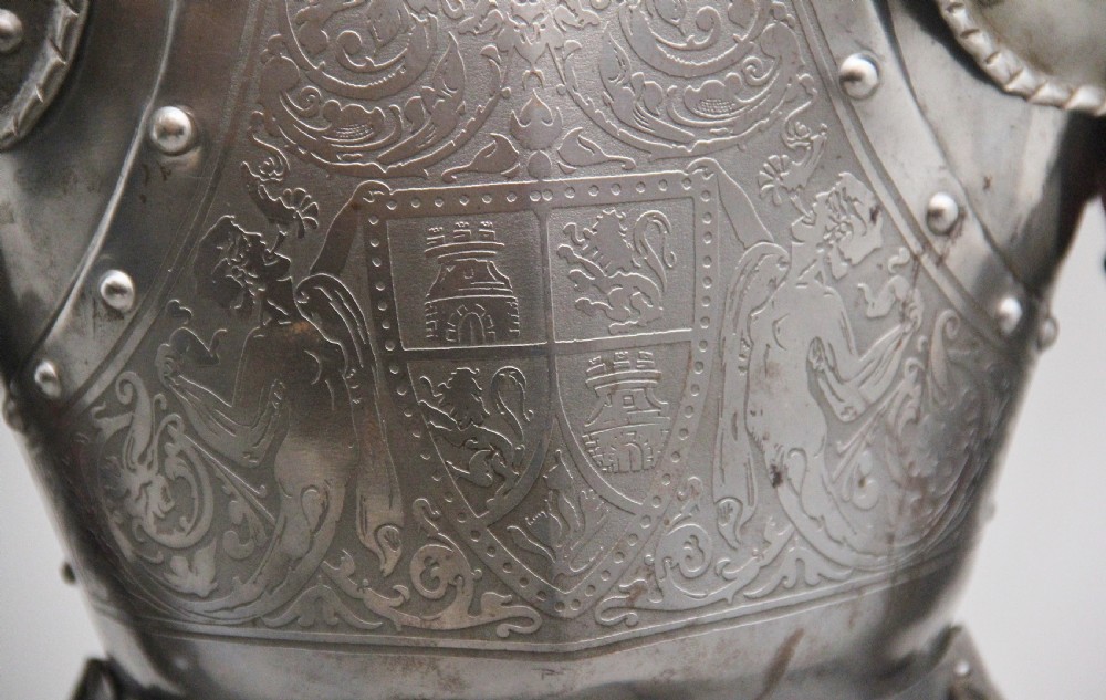 A detailed miniature suit of polished steel plate armour with fine surface etchings, brass eagle emblems, and red fabric lining, standing on a dark wood base. View XIII