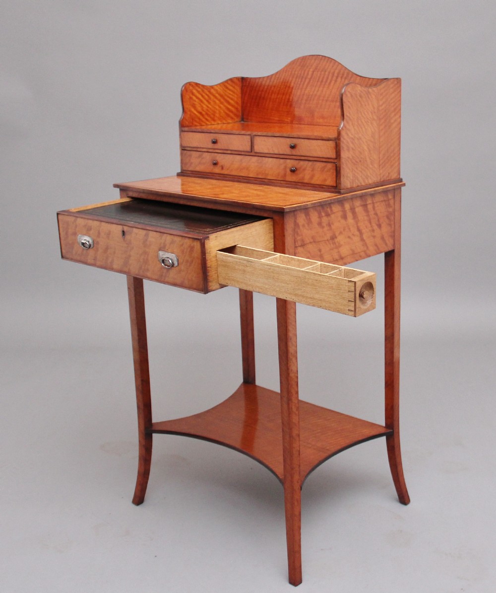 A 19th-century satinwood ladies writing table featuring a raised gallery back with small drawers, a single frieze drawer, square tapered legs, and a curved lower shelf. View II