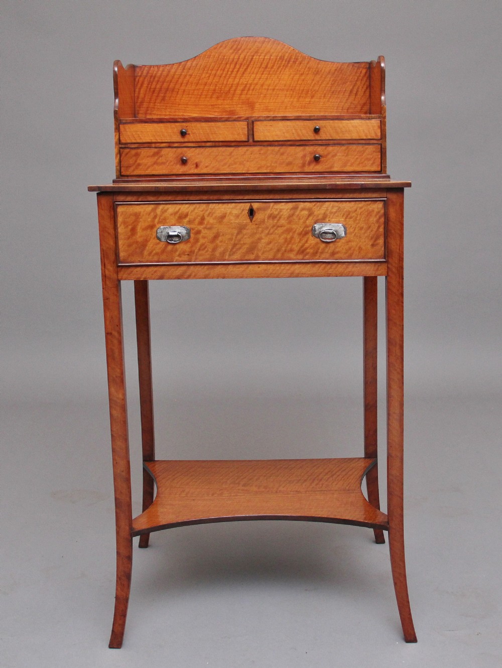 A 19th-century satinwood ladies writing table featuring a raised gallery back with small drawers, a single frieze drawer, square tapered legs, and a curved lower shelf. View VI