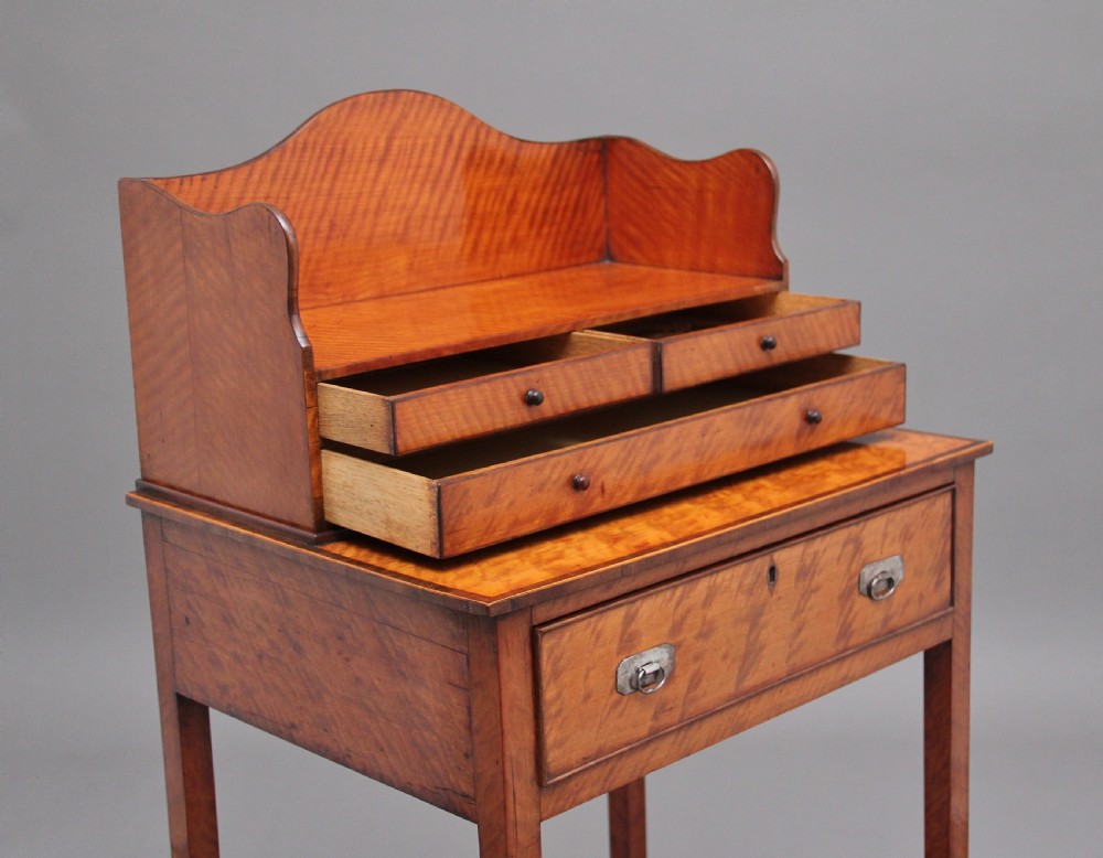 A 19th-century satinwood ladies writing table featuring a raised gallery back with small drawers, a single frieze drawer, square tapered legs, and a curved lower shelf. View VIII