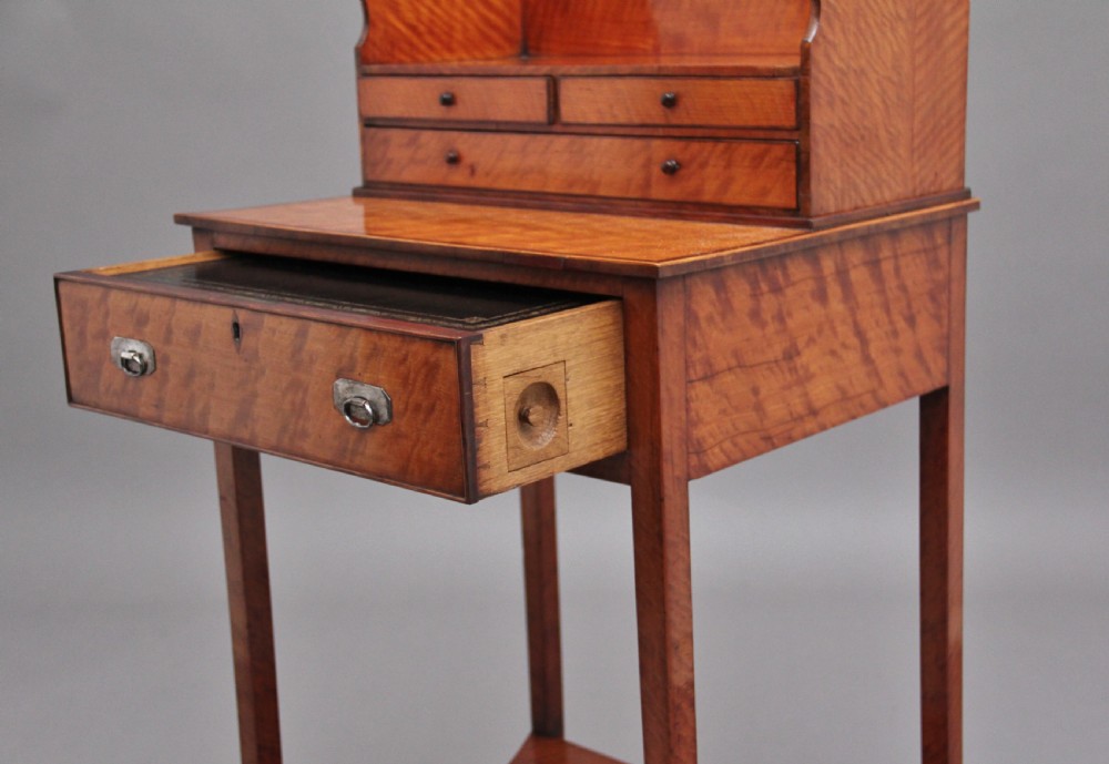 A 19th-century satinwood ladies writing table featuring a raised gallery back with small drawers, a single frieze drawer, square tapered legs, and a curved lower shelf. View XIV