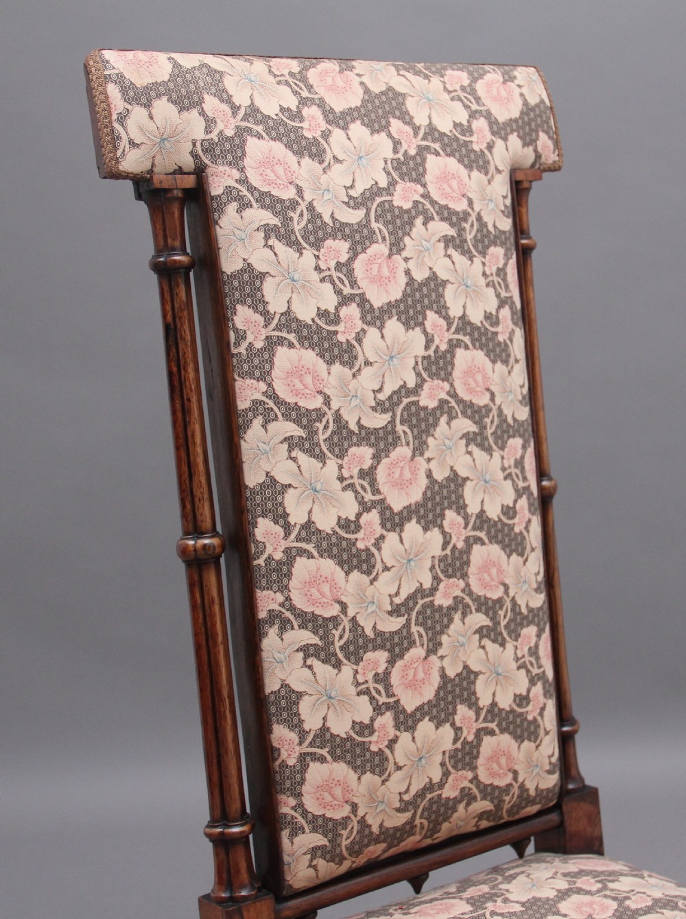 An early 19th-century Gothic Revival rosewood side chair featuring a tall upholstered back, floral pattern fabric, and clustered column turned legs. View VI