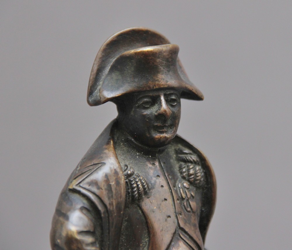 A dark bronze equestrian sculpture depicting Napoleon Bonaparte on horseback mounted on a stepped brass and black marble plinth. View VII