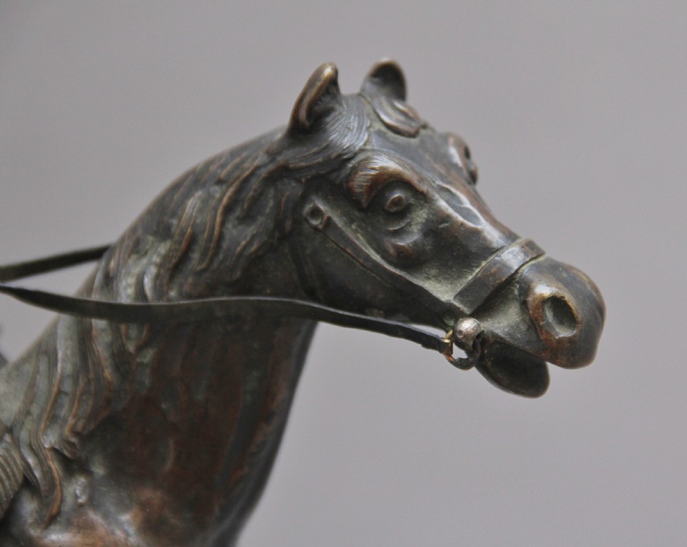 A dark bronze equestrian sculpture depicting Napoleon Bonaparte on horseback mounted on a stepped brass and black marble plinth. View VIII